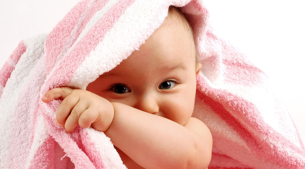 cute baby 9 months peeping behind  a towel 